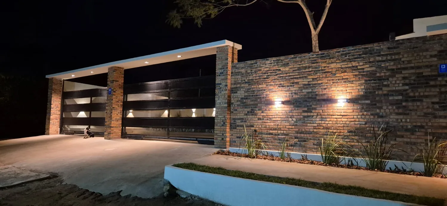 Acceso vehicular con revestimiento de ladrillo e iluminación nocturna